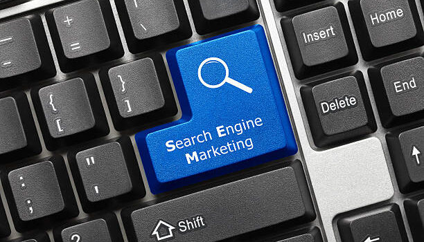 Close-up view on conceptual keyboard - Search Engine Marketing (blue key with magnifying glass symbol)